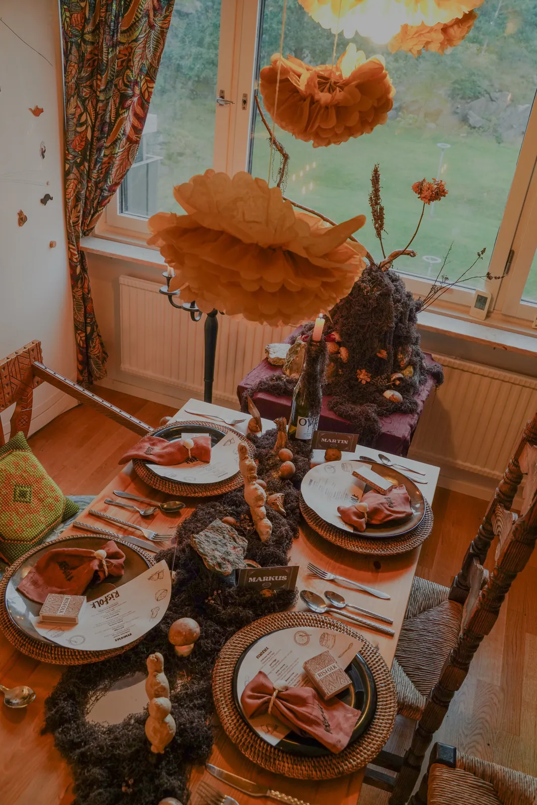 The Risfolk table set with moss, mushrooms, ginger roots, rattan chargers, and paper menus