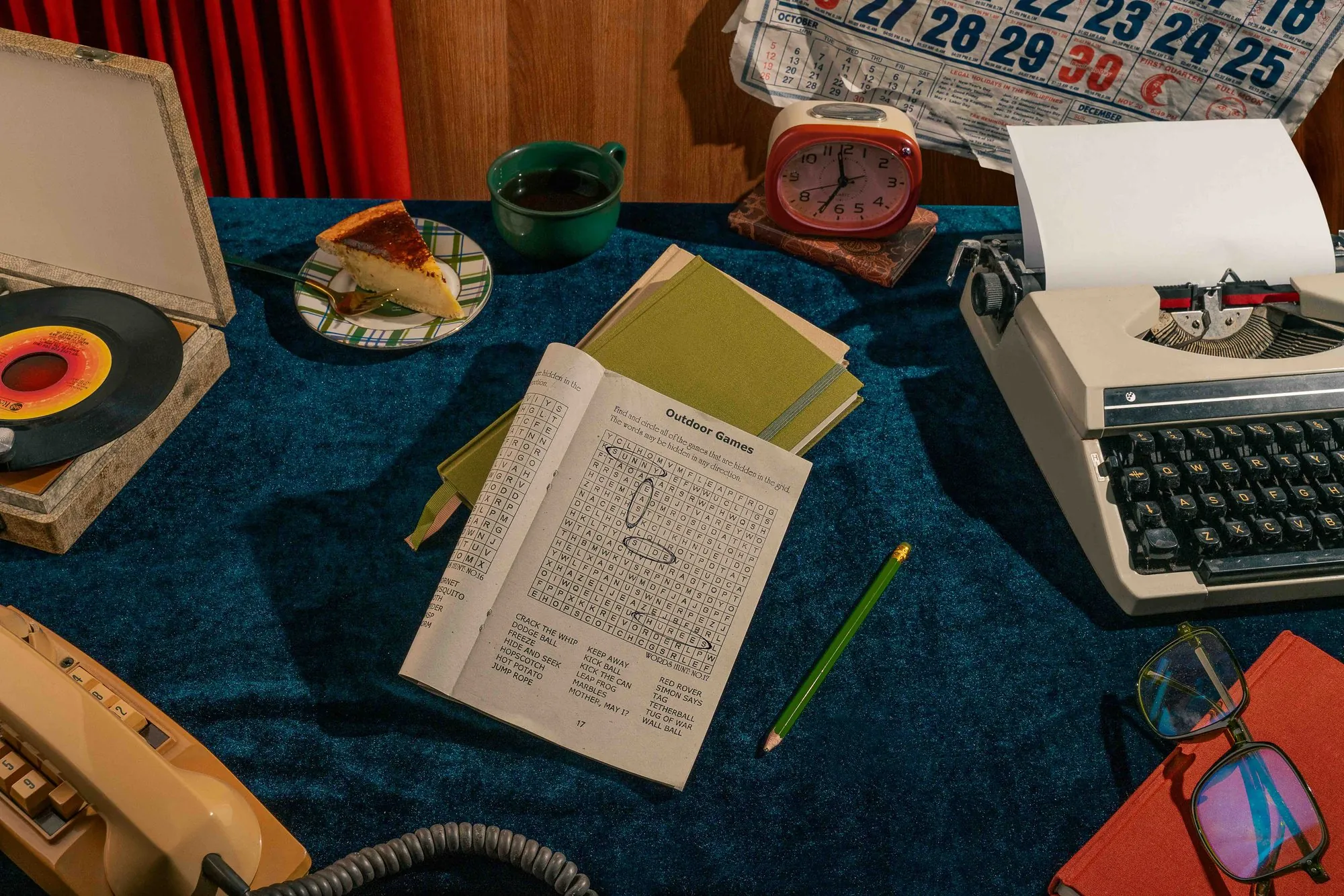 A crossword, typewriter, and record player on a blue velvet table